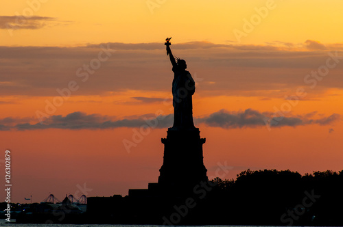 Statue of Liberty silhouette against crimson sunset