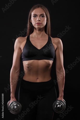 sporty muscular woman working out with dumbbells