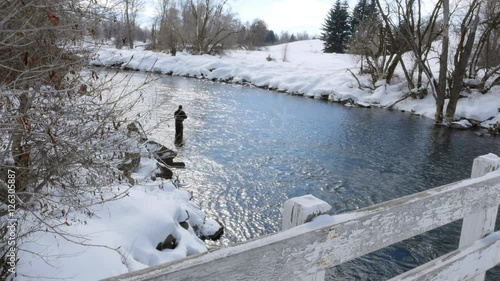 A dolly shot of a man fly fishing in a river