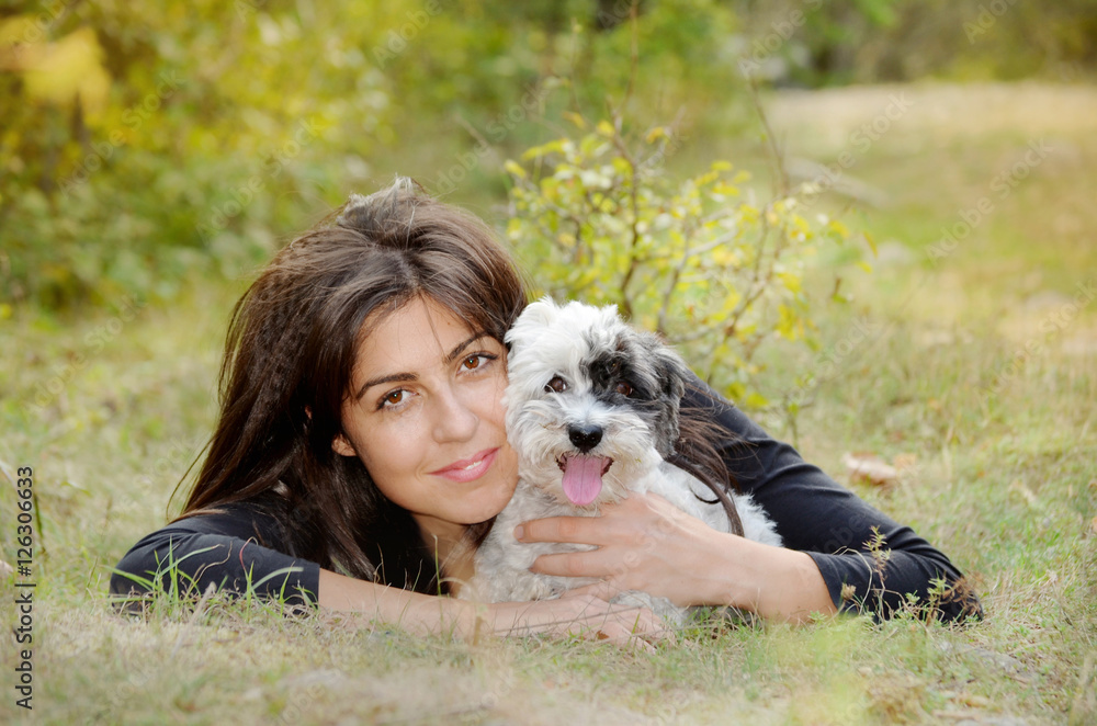 smiling woman laying on a meadow with her small havanese dog smiling woman laying on a meadow with her small havanese dog