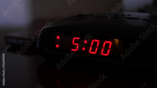 A digital alarm turns five and man turns off alarm