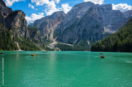 View of scenic turquoise Lake Braies in the Dolomites with the mountain in the background, Sudtirol, Italy. Boat sailing on the lake on a beautiful sunny day.