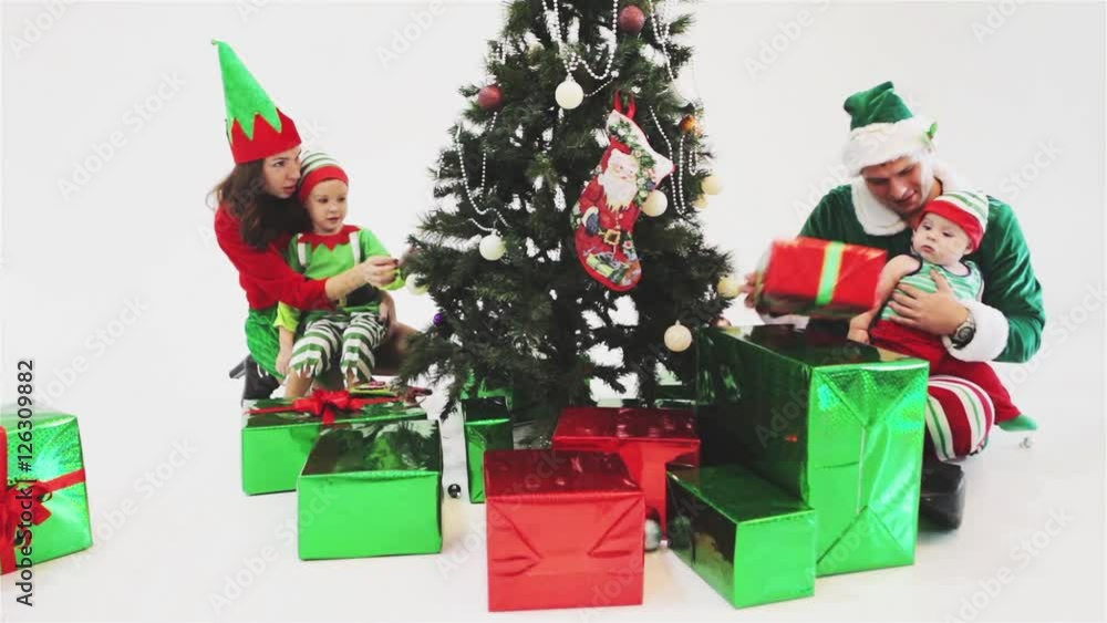 Happy family decorating Christmas tree, dressed in elf costumes Happy family decorating Christmas tree, dressed in elf costumes