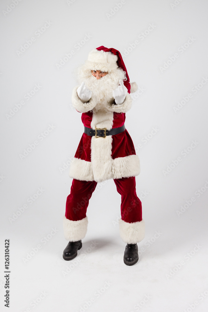 Santa Claus in eyeglasses and red costume standing on white background make a point with hands and looking into camera. Medium long shot Santa Claus in eyeglasses and red costume standing on white background make a point with hands and looking into camera. Medium long shot