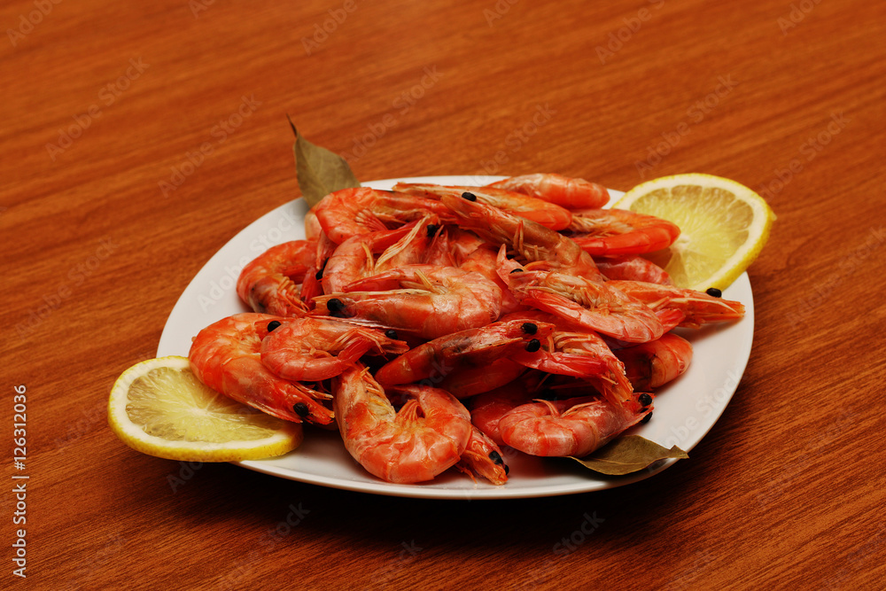 Tasty cooked shrimp lying on a plate with lemon and a variety of spices. Tasty cooked shrimp lying on a plate with lemon and a variety of spices.
