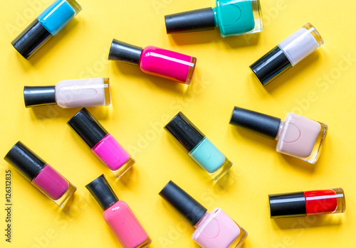 lot of bottles nail polish on yellow background top view