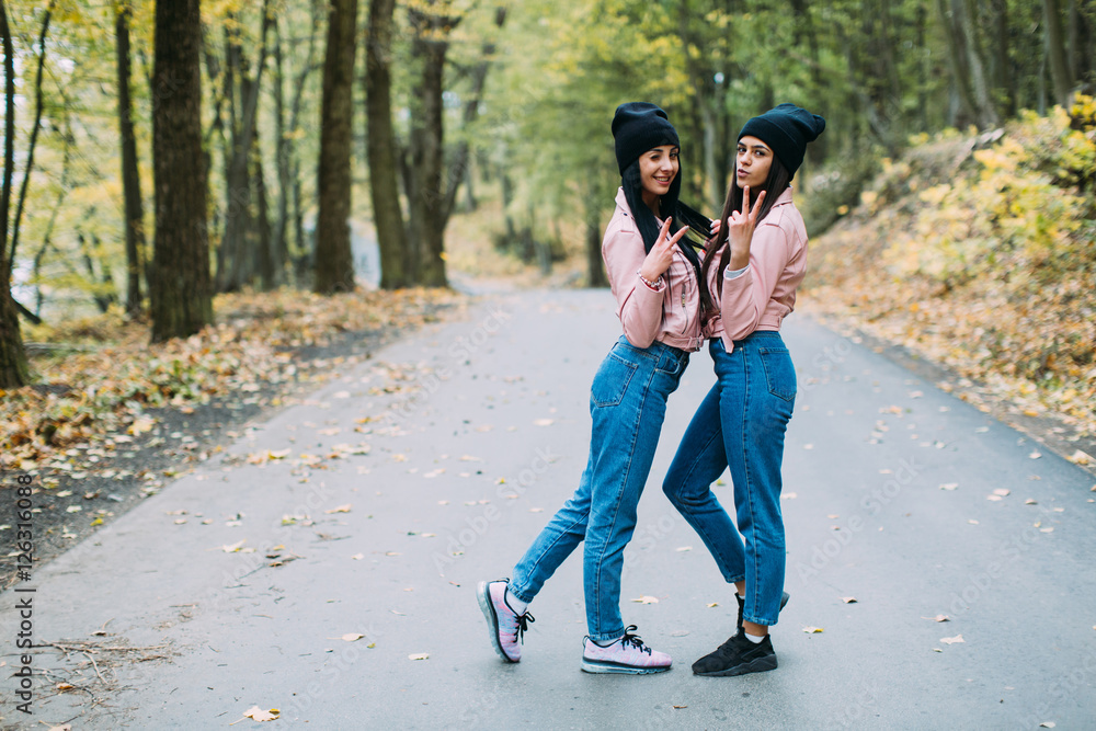 Two stylish, sexy and fashionable girls posing in autumn park Two stylish, sexy and fashionable girls posing in autumn park