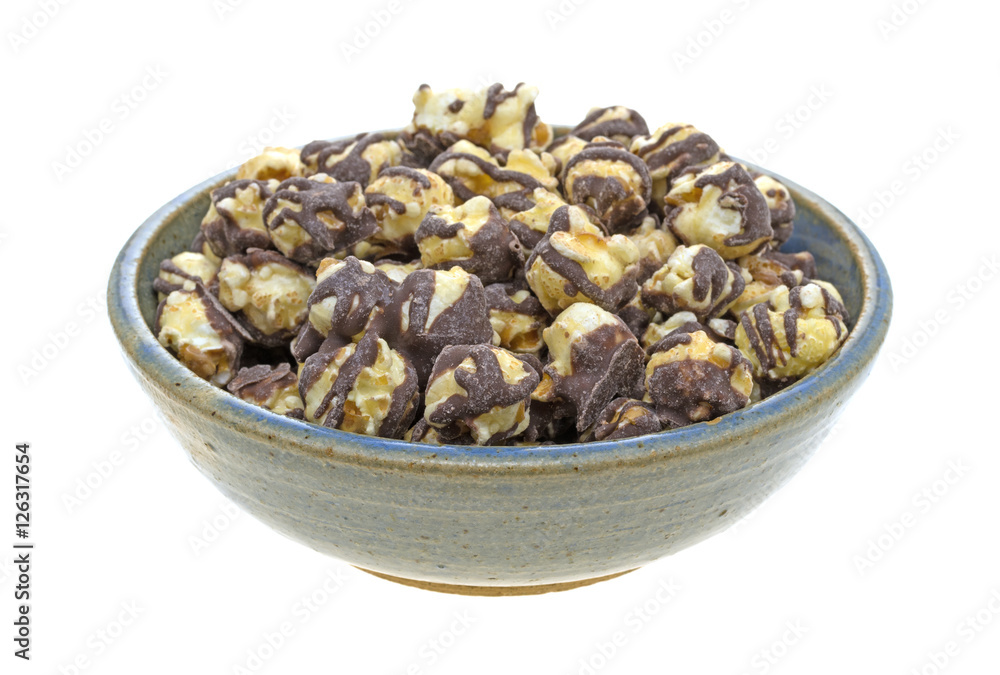 Fudge drizzled popcorn in an old bowl side view isolated on a white background. Fudge drizzled popcorn in an old bowl side view isolated on a white background.