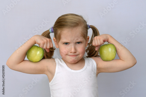 little girl with green apples showing biceps.