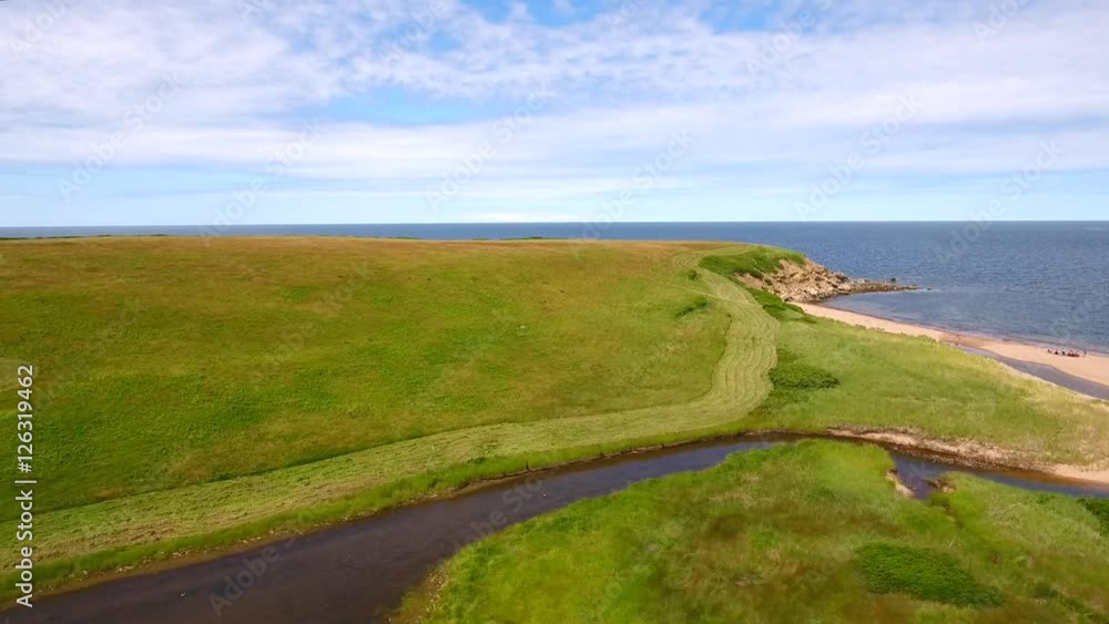 Aerial farmer cuts grass on field by ocean cove Aerial farmer cuts grass on field by ocean cove