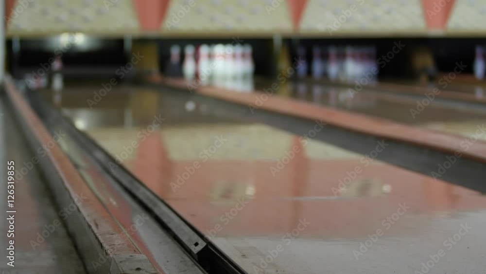 Woman hits pins with bowling ball in bowling alley Woman hits pins with bowling ball in bowling alley