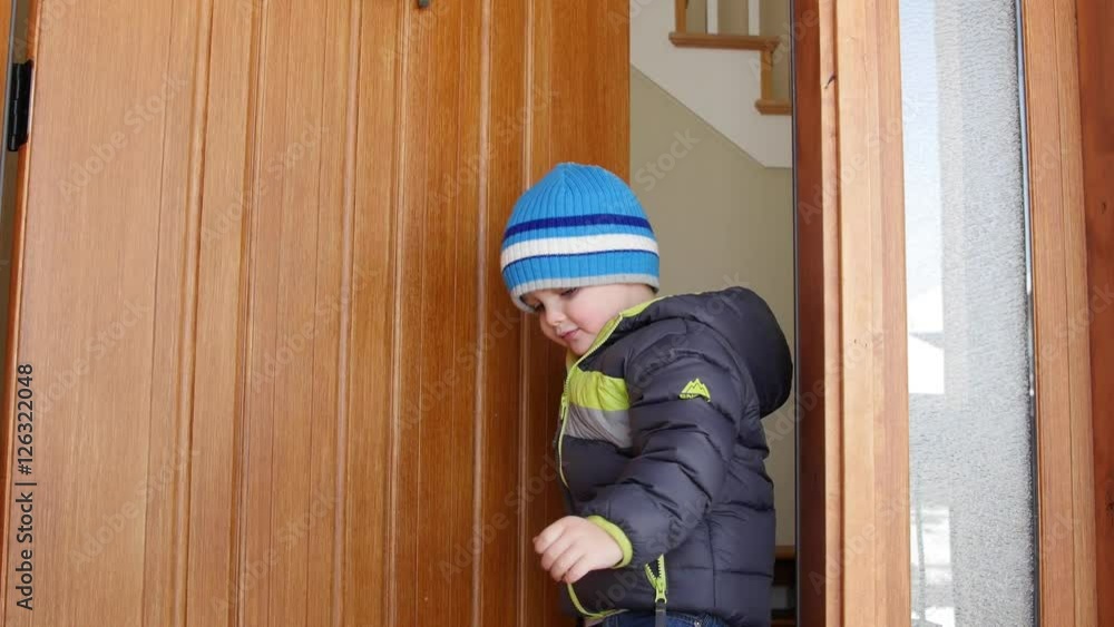 Little boy in coat opens the house door and exits Little boy in coat opens the house door and exits