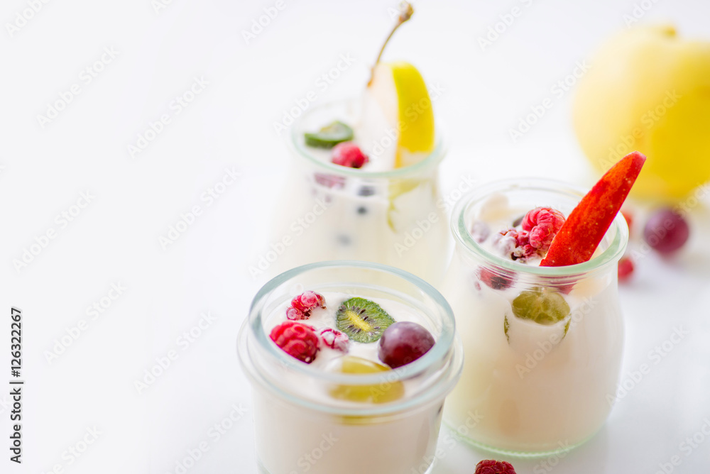 jars with yogurt and colorful fruits on a white background. jars with yogurt and colorful fruits on a white background.