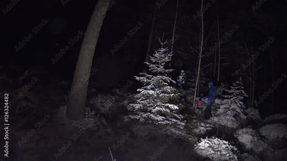 Two girls kid and teen play in winter forest with a flashlight and a toy shovel in dark evening Two girls kid and teen play in winter forest with a flashlight and a toy shovel in dark evening
