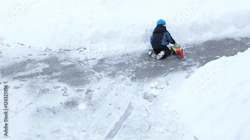 A little boy playing with toy tractor in snow photo