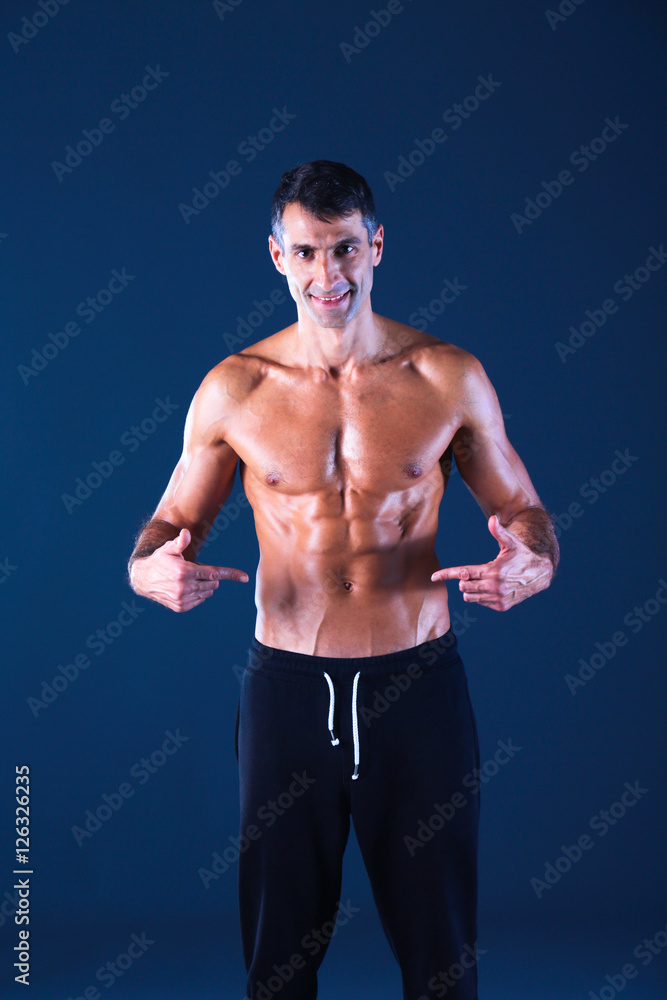 Fototapeta premium Strong athletic man standing on black background