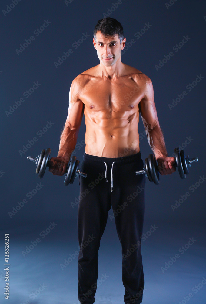 Handsome muscular man working out with dumbbells Handsome muscular man working out with dumbbells