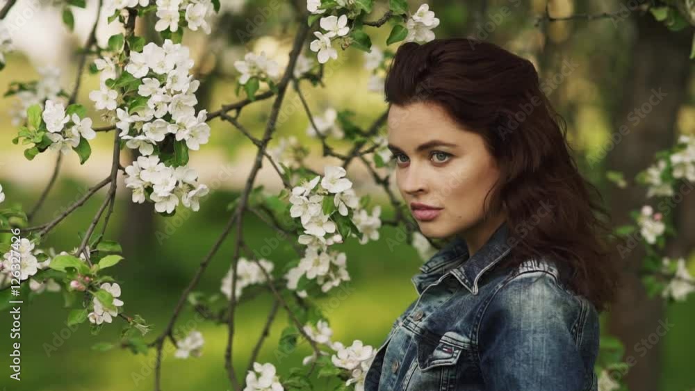 Young pretty caucasian woman in jeans jacket standing near blooming spring tree. Youth, freshness, beauty, happiness concept. Young pretty caucasian woman in jeans jacket standing near blooming spring tree. Youth, freshness, beauty, happiness concept.