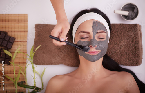 Photography Hands of cosmetologist apply cream to half-face of woman with closed eyes