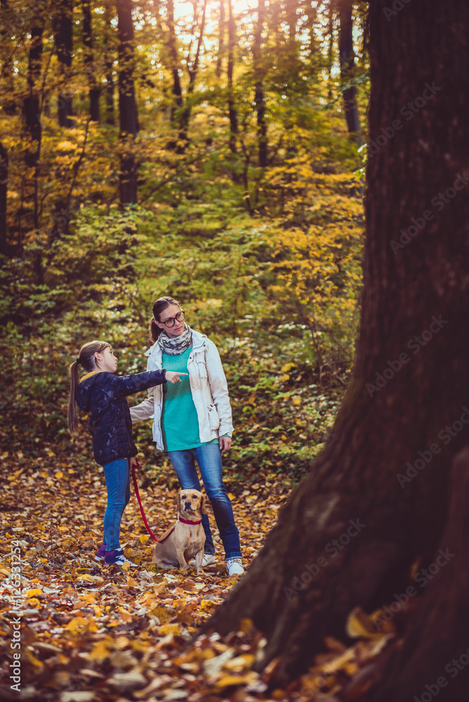 Mother and daughter with dog hiking in a forest