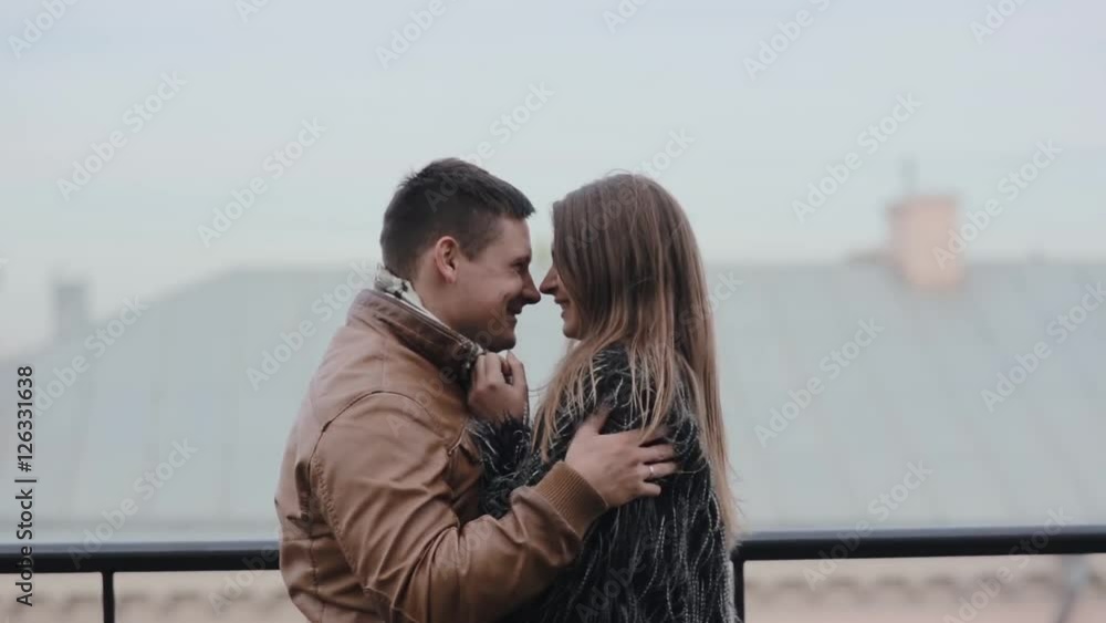 Beautiful young couple tenderly hugging, kissing each other. Harmony in relationship. Loving couple on a roof. Beautiful young couple tenderly hugging, kissing each other. Harmony in relationship. Loving couple on a roof.