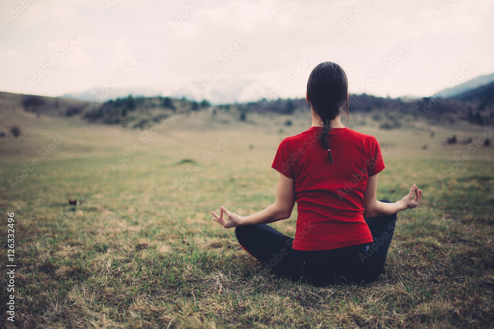 Young woman meditating on a meadow, Daydreaming, well-being and healthy lifestyle. Practicing yoga. Peaceful environment. Focusing.Being in present moment.Mindfulness