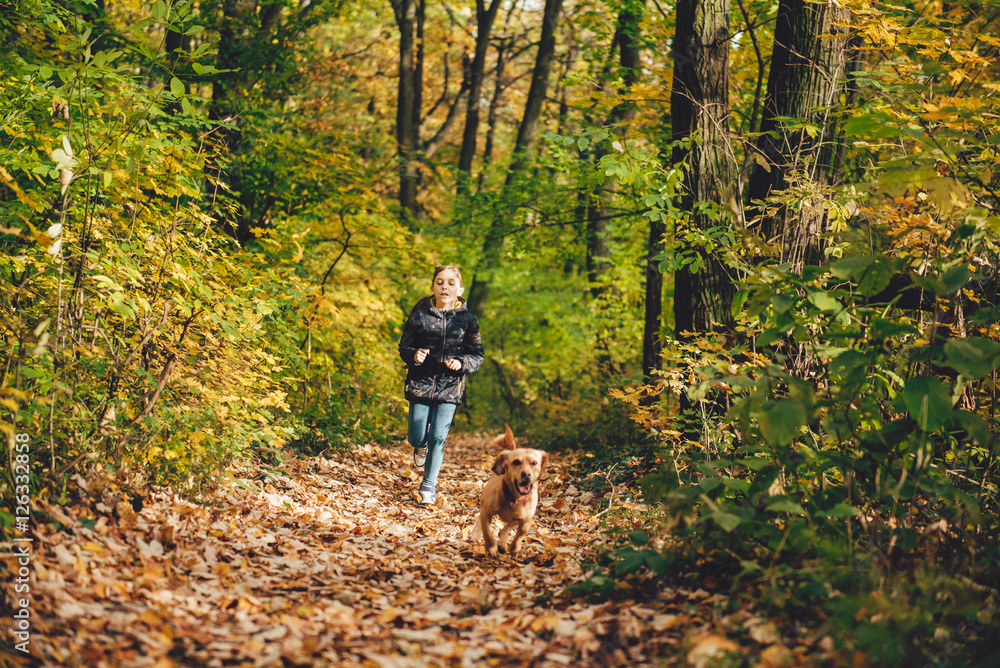 Girl and dog running on forest trail Girl and dog running on forest trail