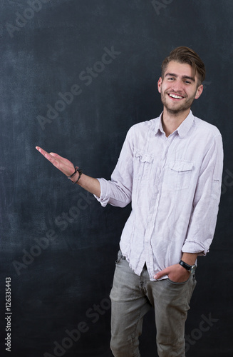 Portrait of young happy smiling teacher man standing near chalkb photo