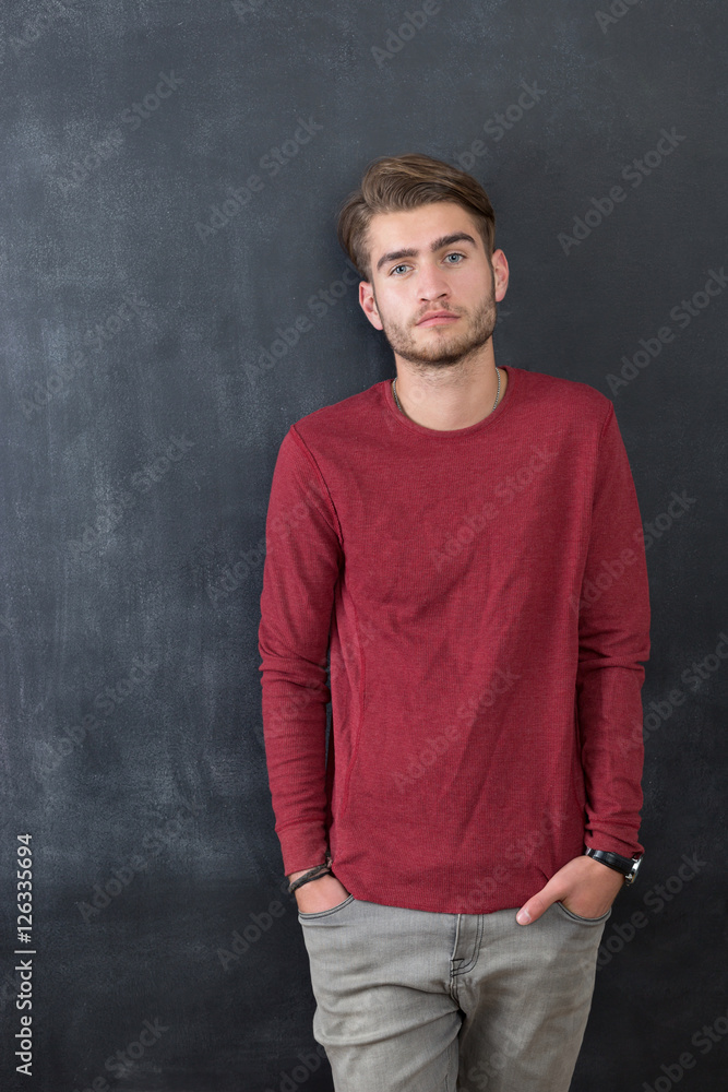 Trendy relaxed young man with a modern haircut standing against