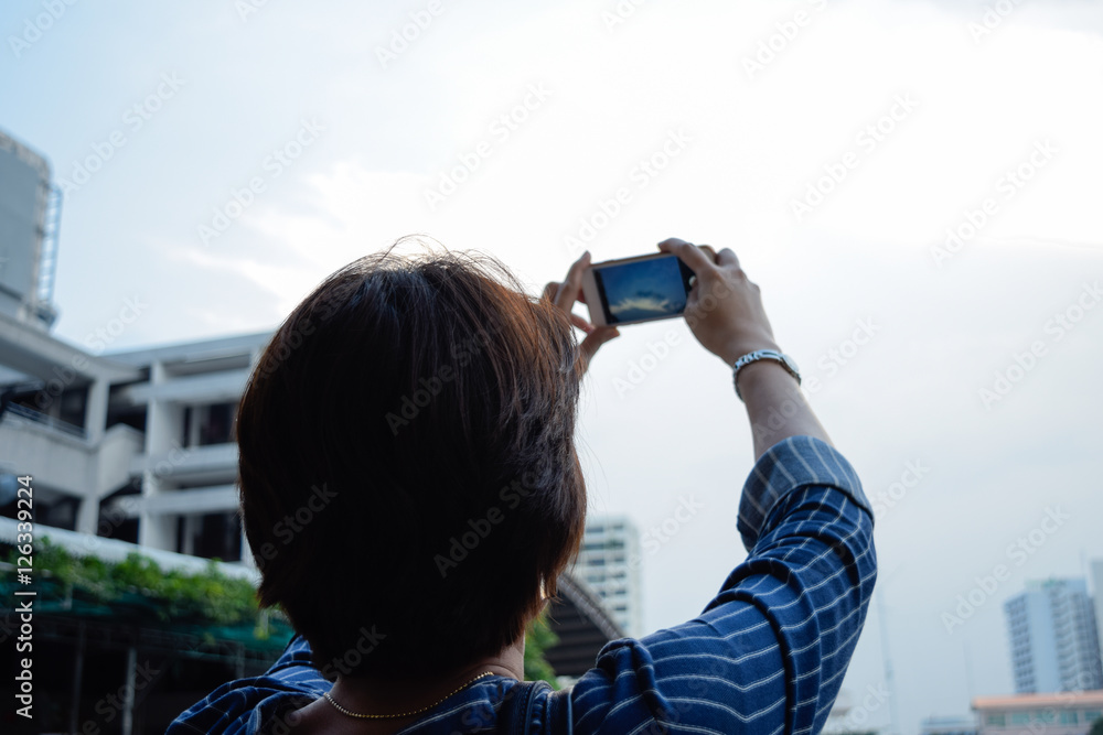 Asian Woman using smart phone to take a picture of sky