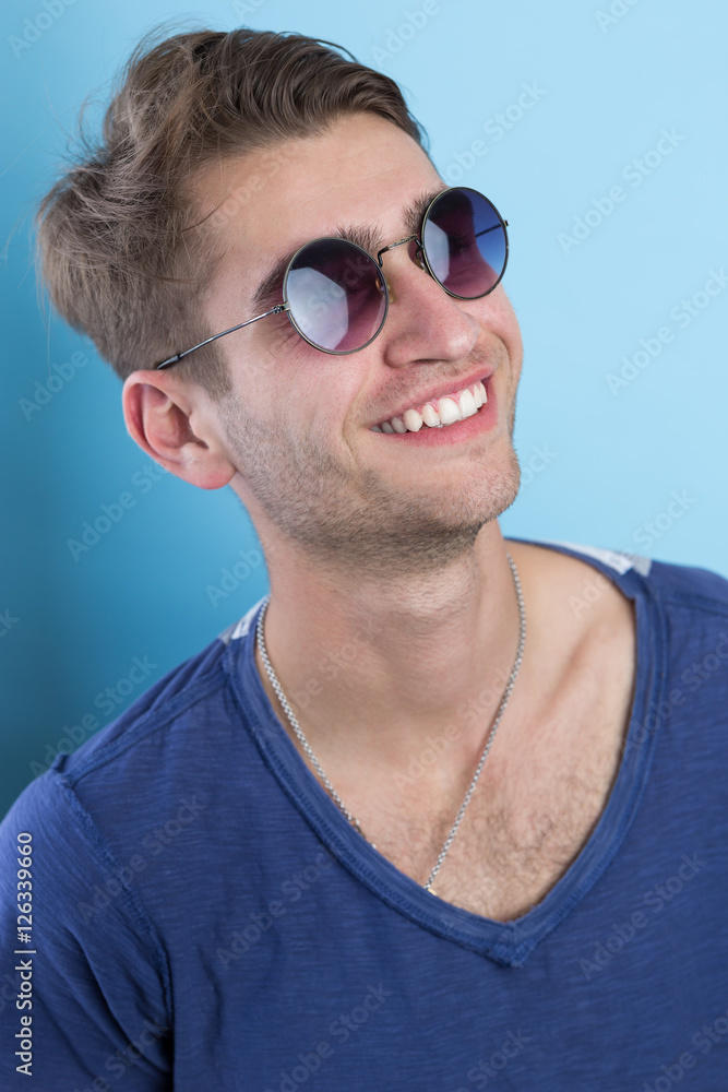 Portrait of an attractive young man laughing against blue backgr Portrait of an attractive young man laughing against blue backgr
