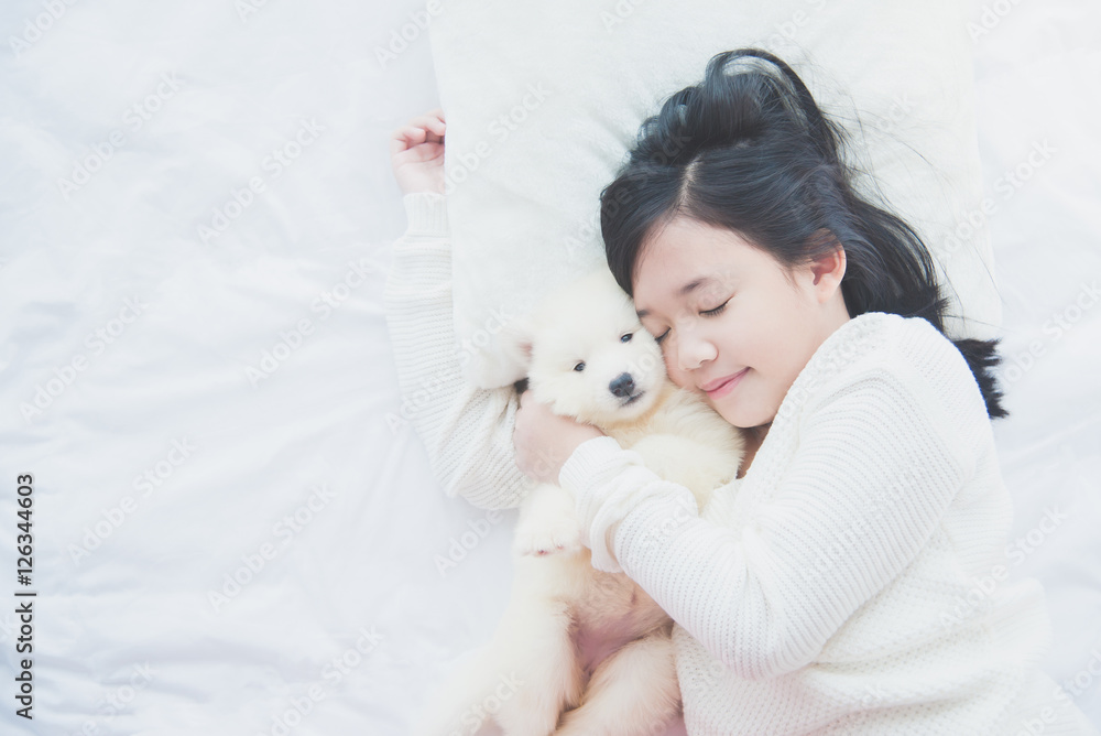 asian girl lying with siberian husky puppy on bed.. asian girl lying with siberian husky puppy on bed..
