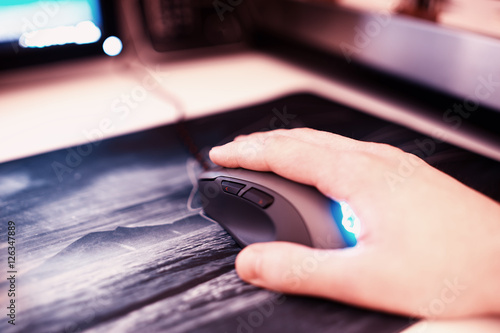 Φωτογραφία Computer mouse with human hand on mousepad bokeh backdrop