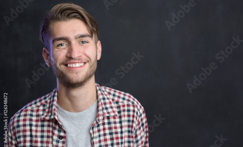 Handsome young student in shirt standing against blackboard © Myvisuals