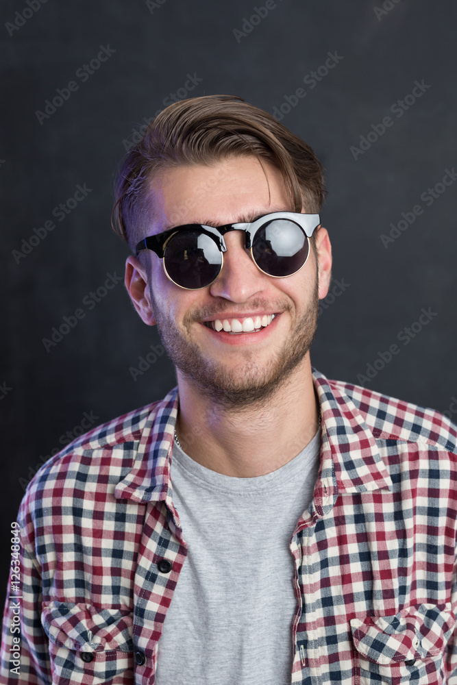 Portrait of a relaxed young man with checkered shirt and sunglas Portrait of a relaxed young man with checkered shirt and sunglas