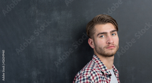 Trendy relaxed young man with a modern haircut standing against