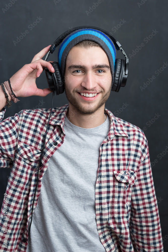 Carefree music lover. Joyful young man in headphones smiling aga Carefree music lover. Joyful young man in headphones smiling aga