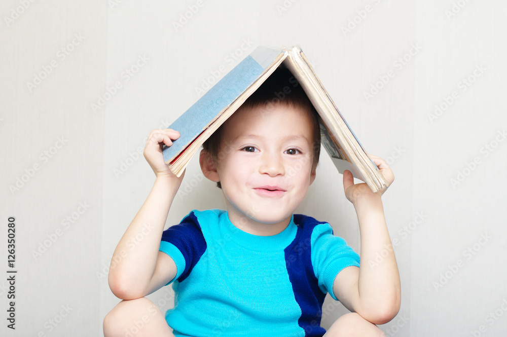 Happy boy making roof with book Happy boy making roof with book