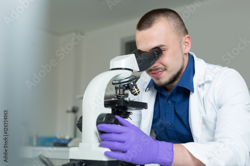 Young scientist investigating microbiological substance in micro