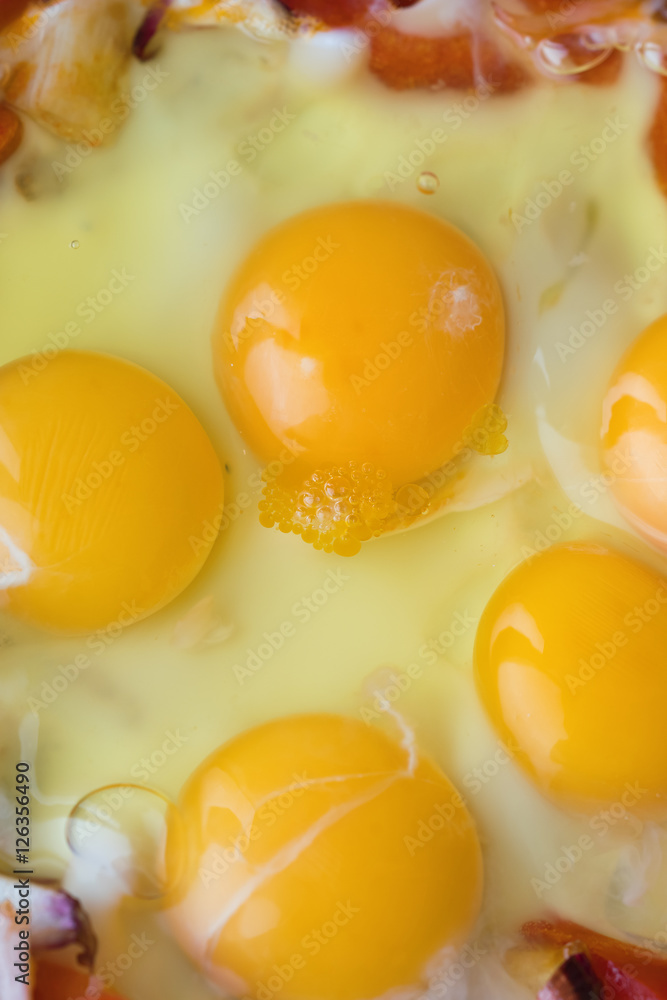 Raw fried eggs with tomatoes and onion, background Raw fried eggs with tomatoes and onion, background