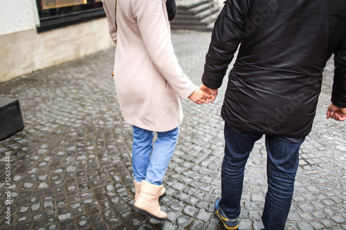 Young couple holding on to his hand, walk in the city