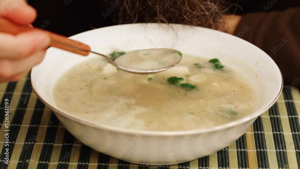 Asian food - man eating chicken coconut soup in dish; closeup; Asian food - man eating chicken coconut soup in dish; closeup;