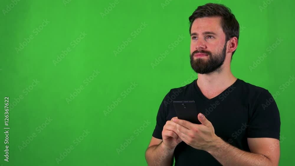 young handsome bearded man works (typing) on smartphone - green screen - studio young handsome bearded man works (typing) on smartphone - green screen - studio