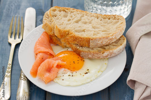 fried egg with smoked salmon and bread on white dish