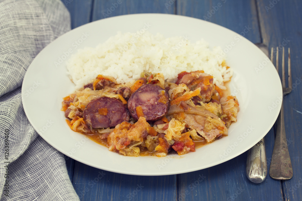 meat with sausages, cabbage and rice on white plate on wooden background meat with sausages, cabbage and rice on white plate on wooden background