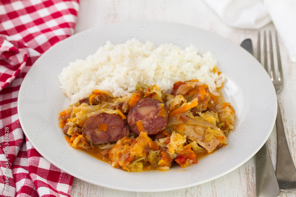 meat with sausages, cabbage and rice on white plate on wooden background meat with sausages, cabbage and rice on white plate on wooden background