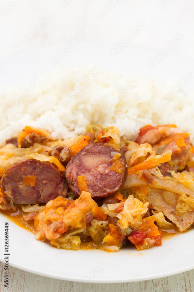 meat with sausages, cabbage and rice on white plate on wooden background meat with sausages, cabbage and rice on white plate on wooden background