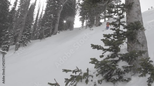 dolly reveal of woman skiing fresh powder snow on a treed slow
