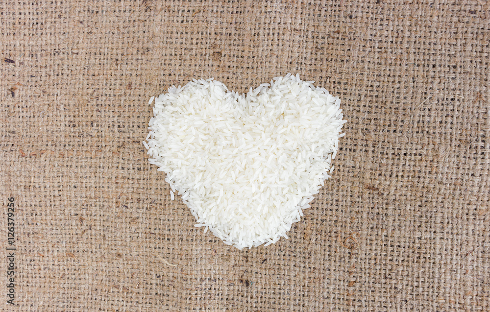 heart shape rice grains on old sack background. over light