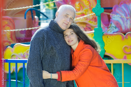 Amusement park outdoor family portrait of hugging adult daughter and senior father